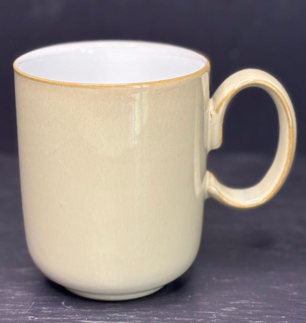 Beige mug with a handle on a dark background
