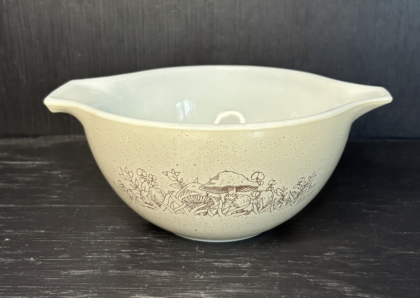 Vintage ceramic mixing bowl with floral pattern on a dark surface
