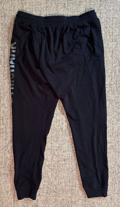 Black jogger pants with a brand logo on a textured surface