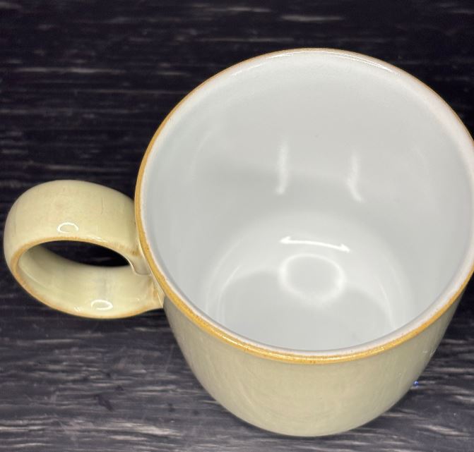 Ceramic mug with a gold rim and handle on a dark surface
