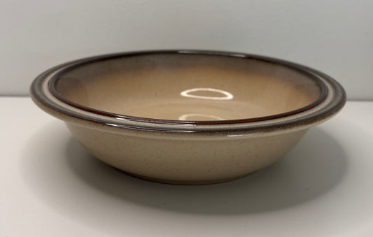Beige ceramic bowl with brown rim on a white background
