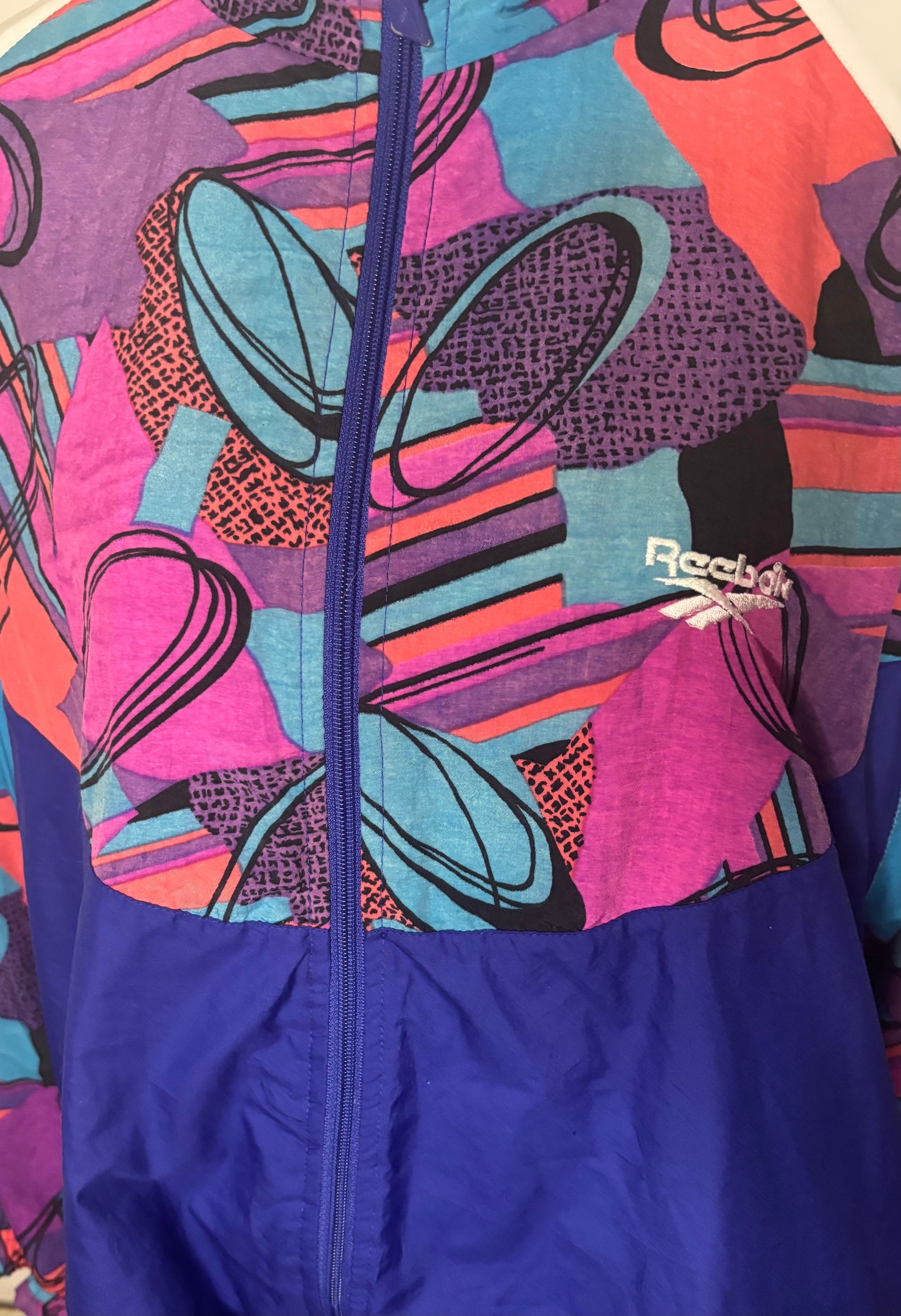 Colorful jacket with abstract patterns and a visible brand logo on a white background