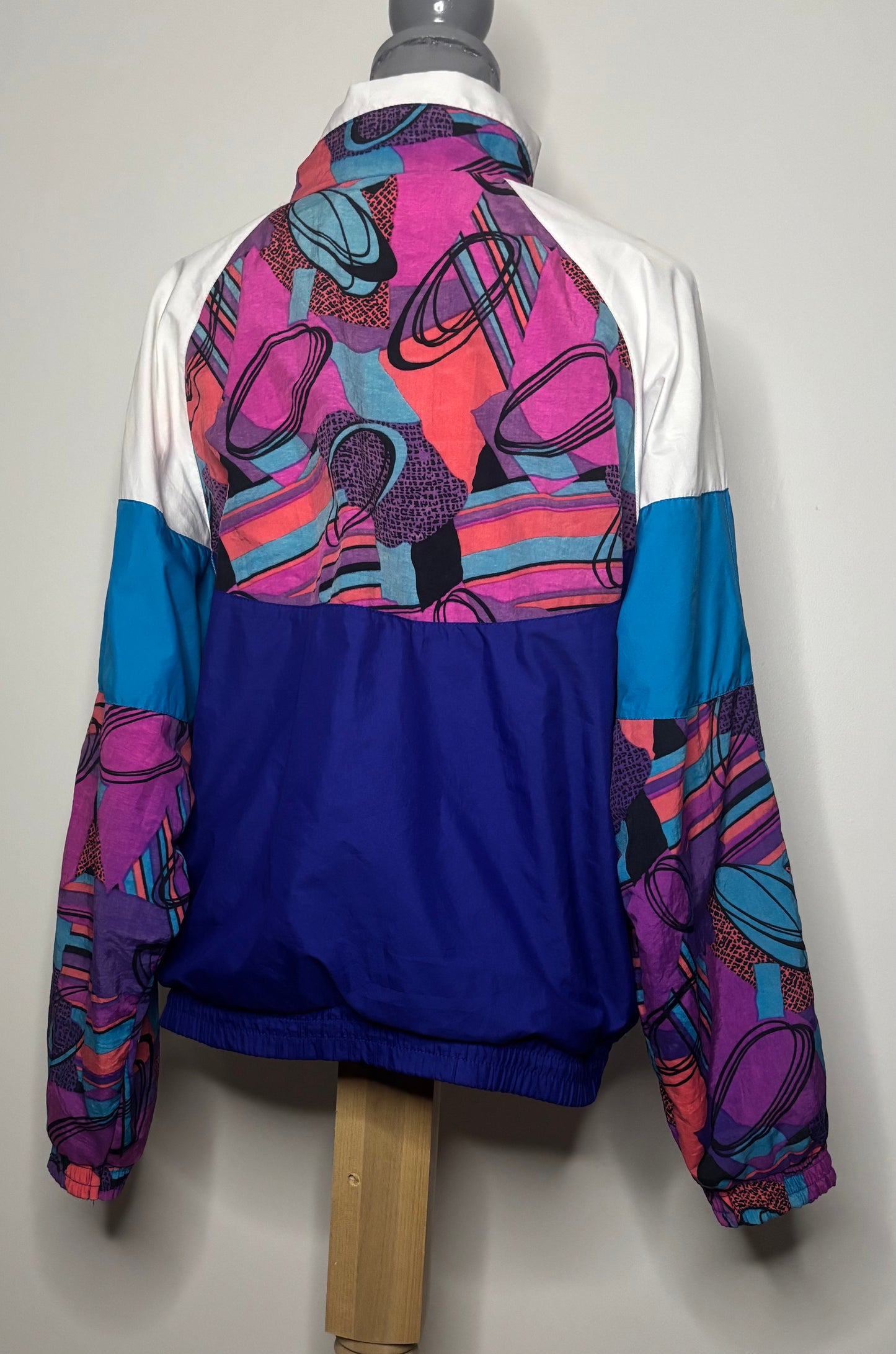 Colorful jacket with abstract pattern on a mannequin against a plain background