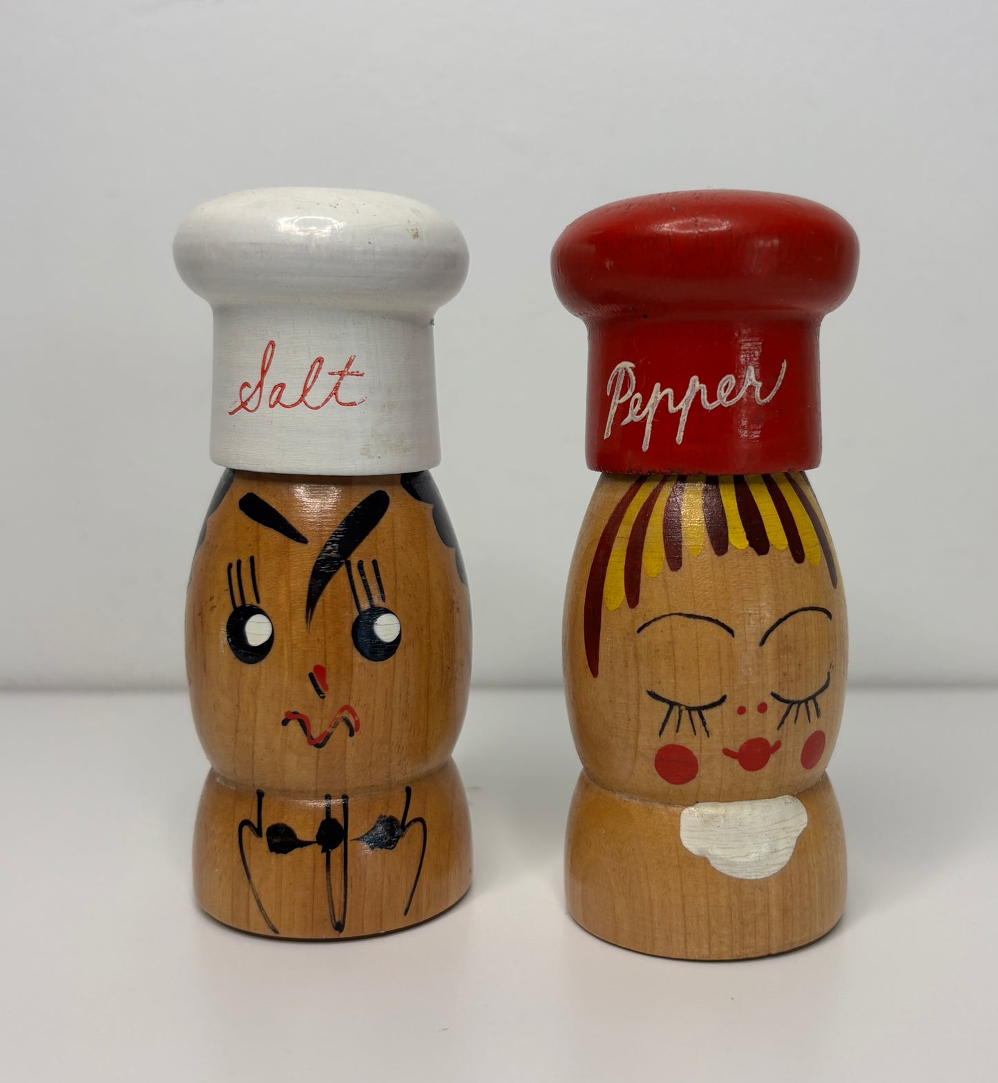 Wooden salt and pepper shakers with faces on a white background