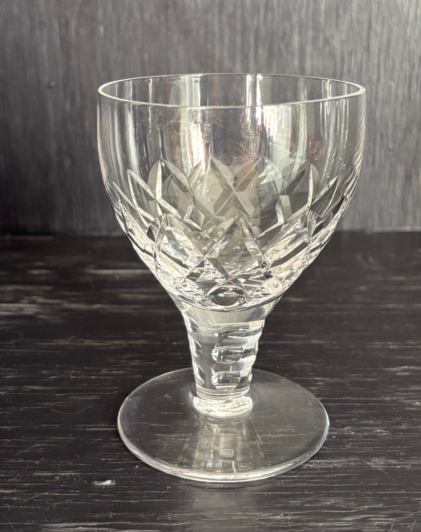 Clear glass goblet with intricate cut patterns on a dark surface