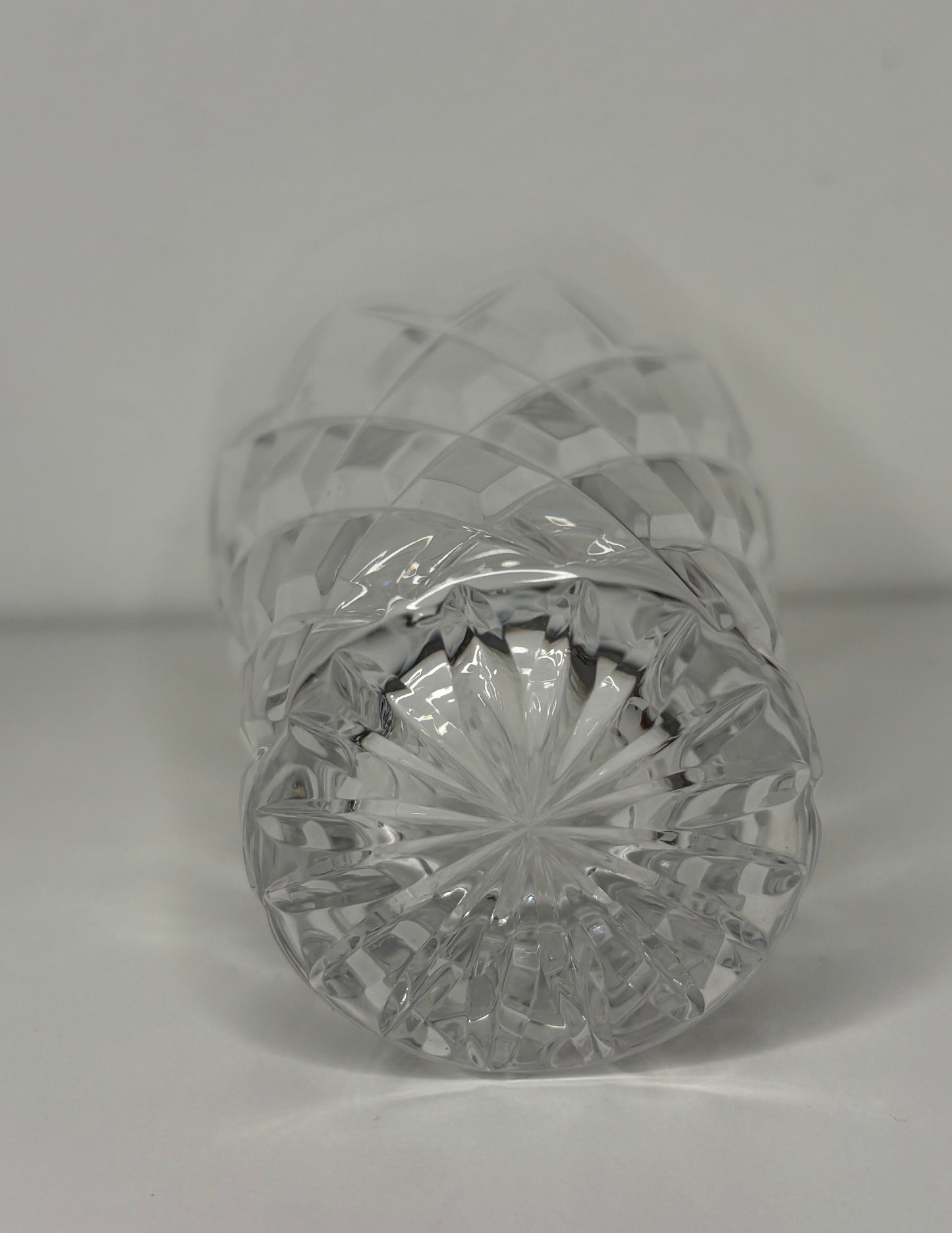 Crystal bottle with cut design on a plain background