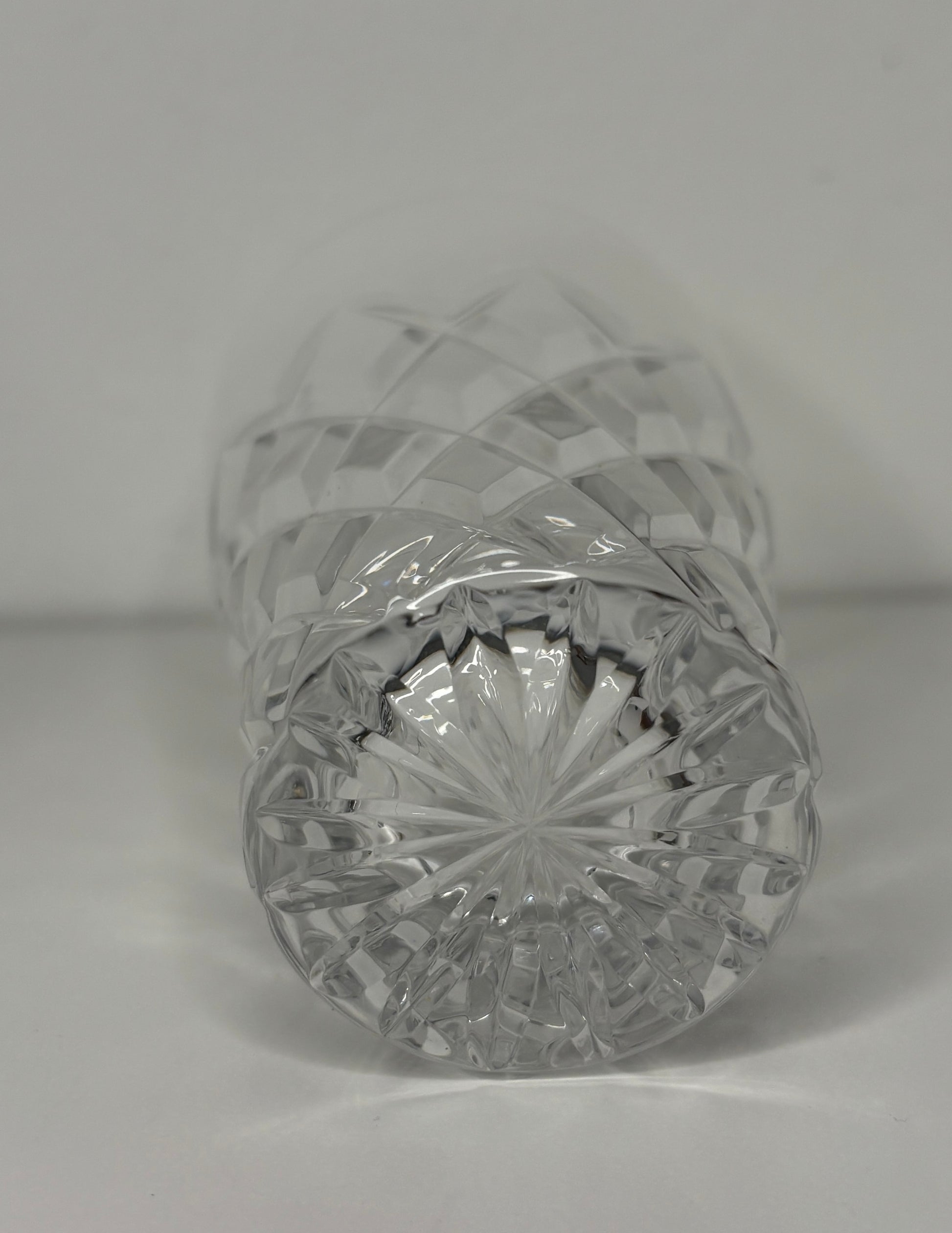 Crystal bottle with cut design on a plain background