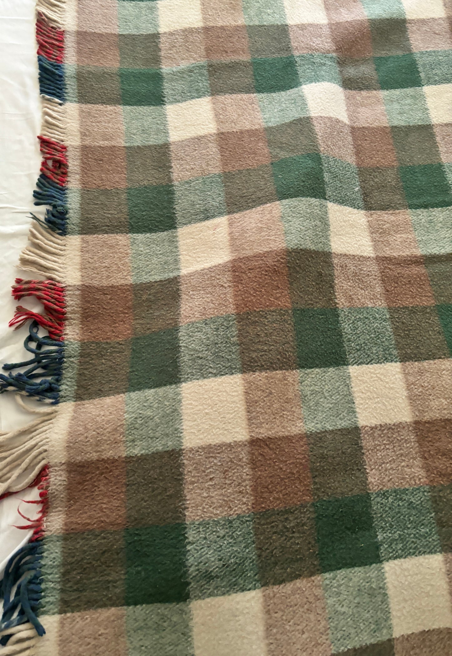 Plaid blanket with brown, green, and beige colors on a white background