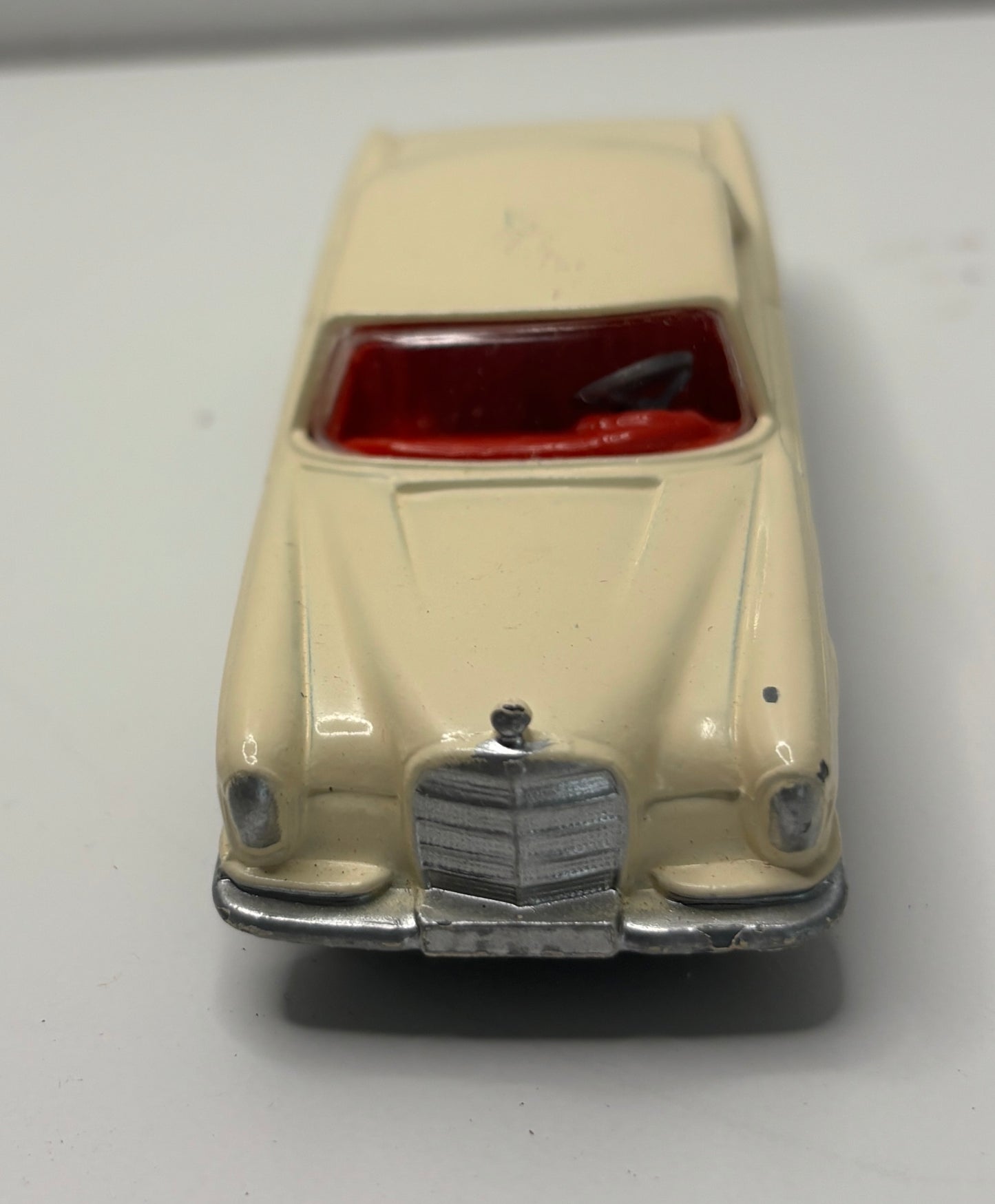 Beige toy car with a red interior on a white background