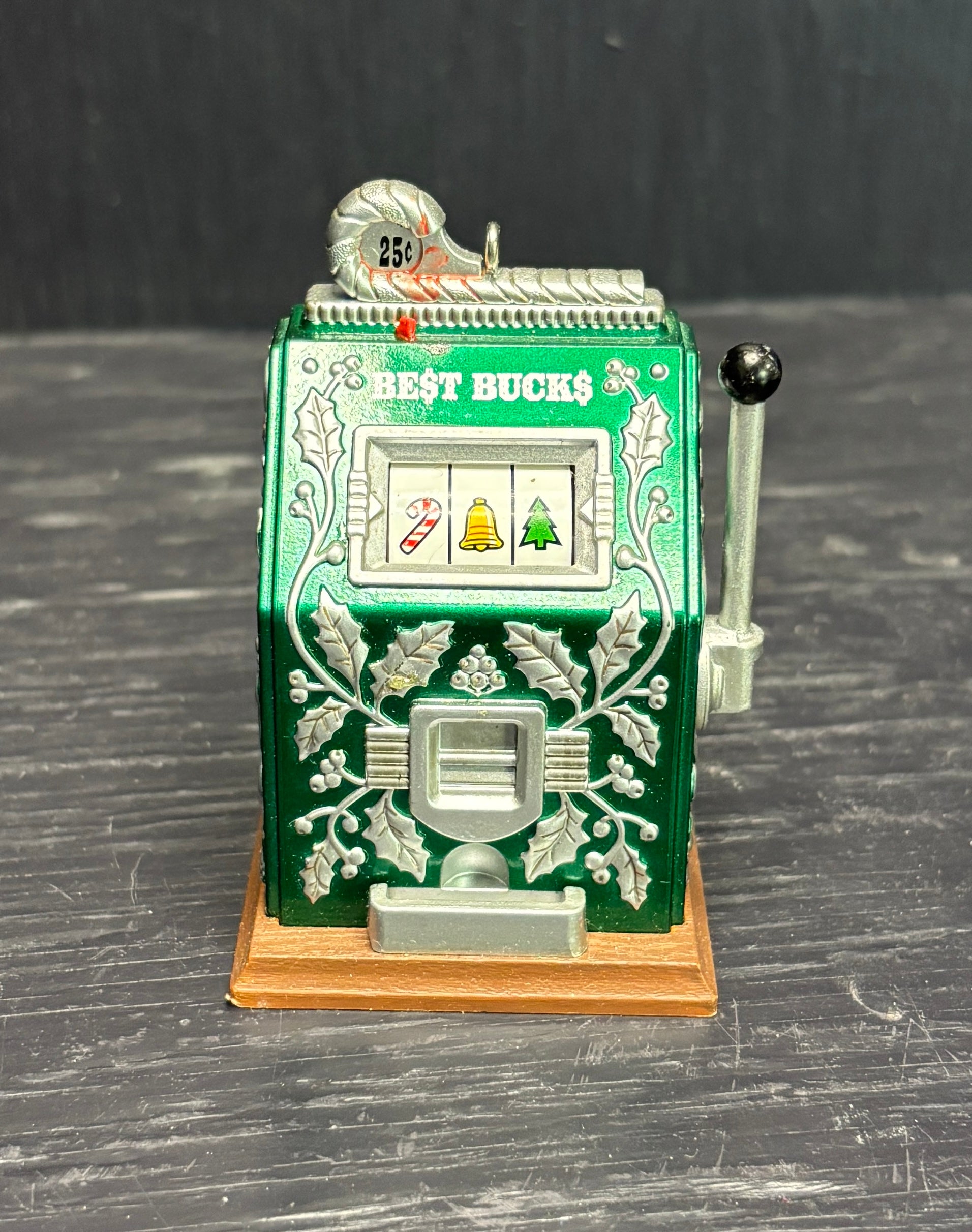 Miniature slot machine with green and silver design on a dark surface