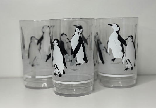 Three glass tumblers with penguin designs on a white background