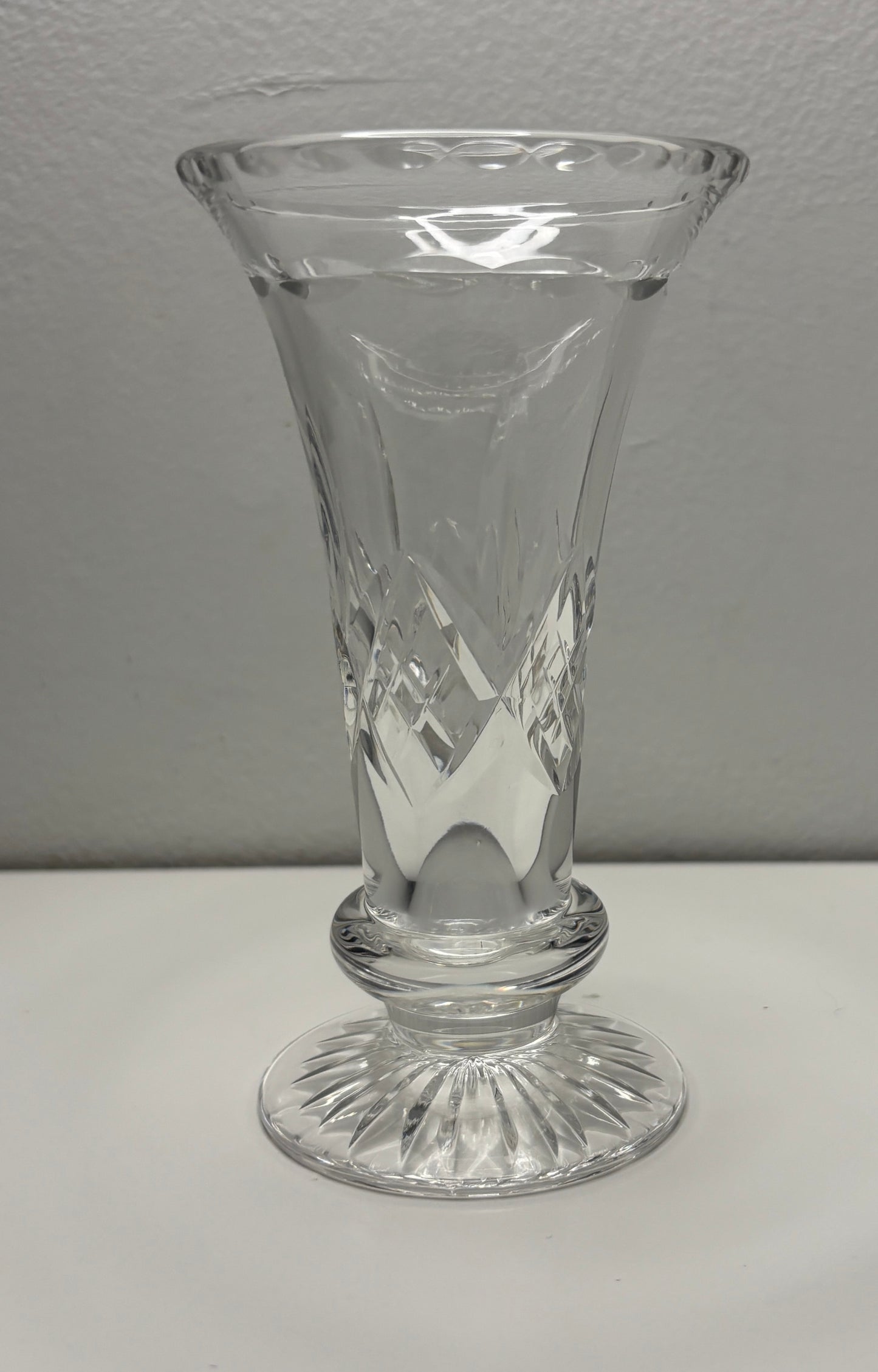 Clear glass vase with etched design on a white surface and gray background