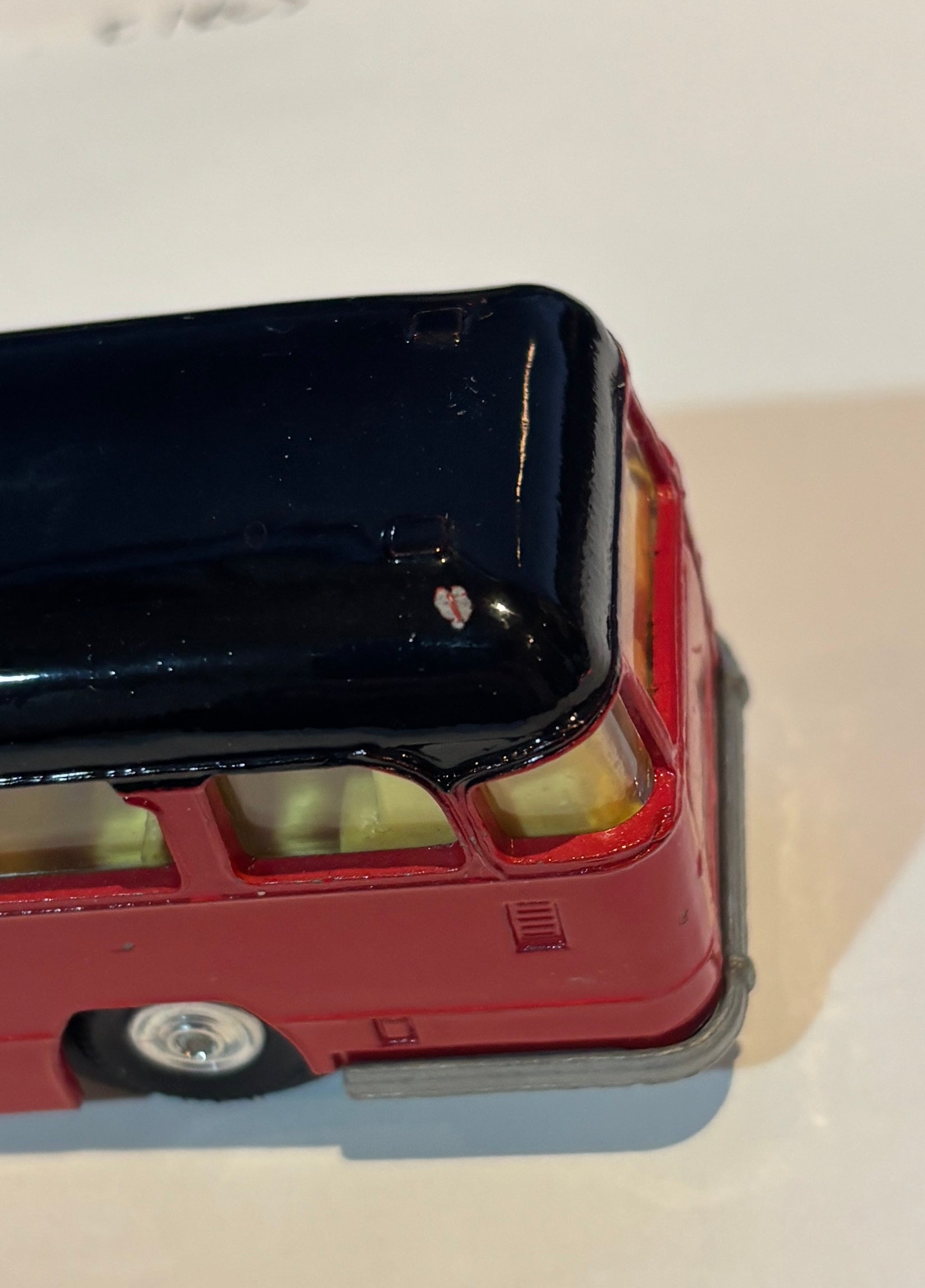 Model of a red double-decker bus with black top on a white background