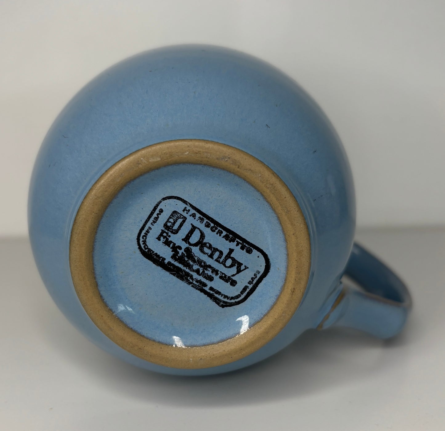 Blue ceramic mug with 'Denby' branding on a white background