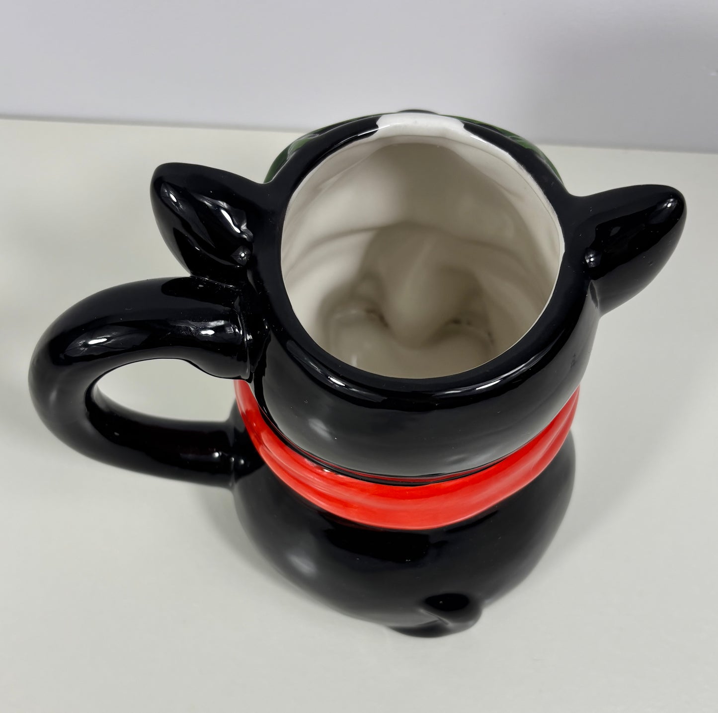 Black dog-shaped mug with red stripe on a white background