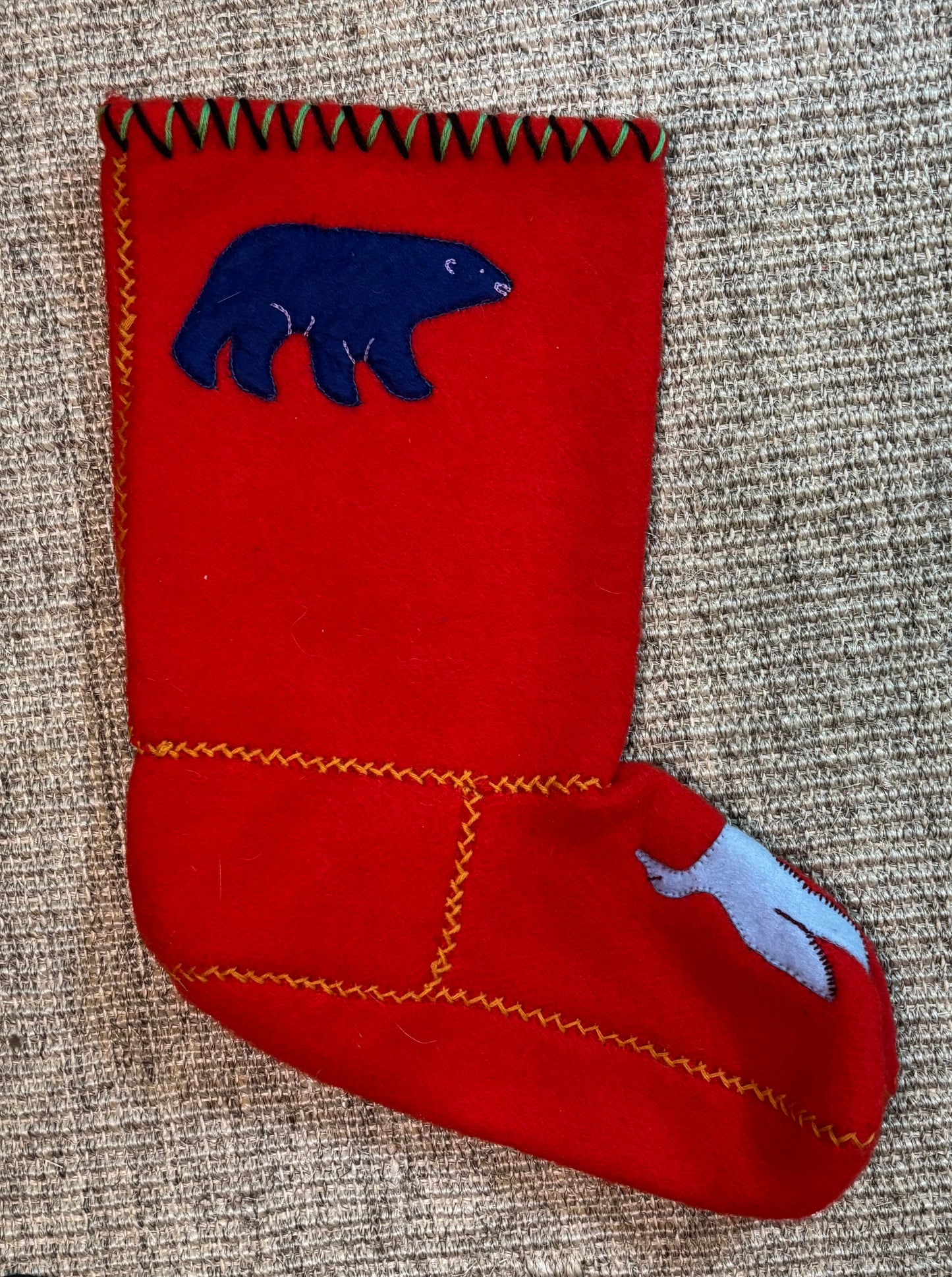 Red felt stocking with blue bear design on a textured surface