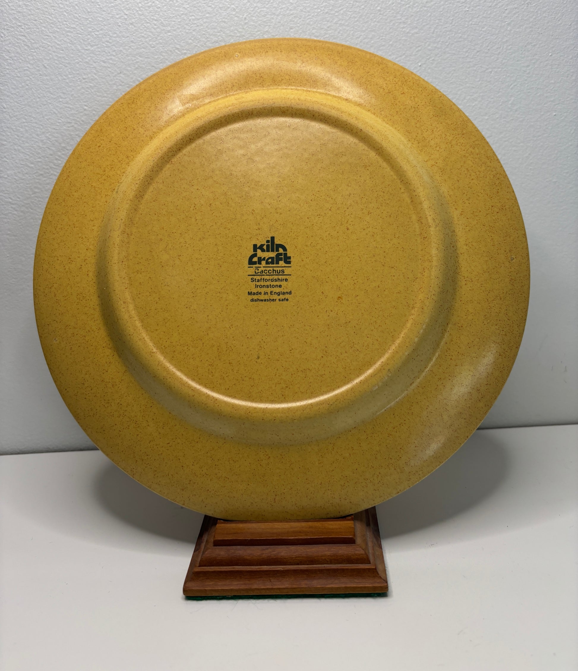 Brown ceramic plate on a stand with 'kiln craft' branding against a gray background
