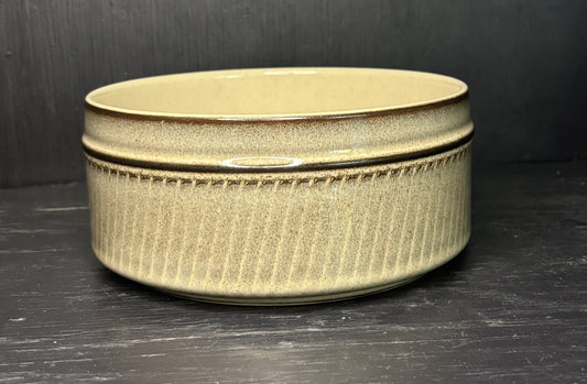 Beige ceramic dish with decorative rim on a dark surface