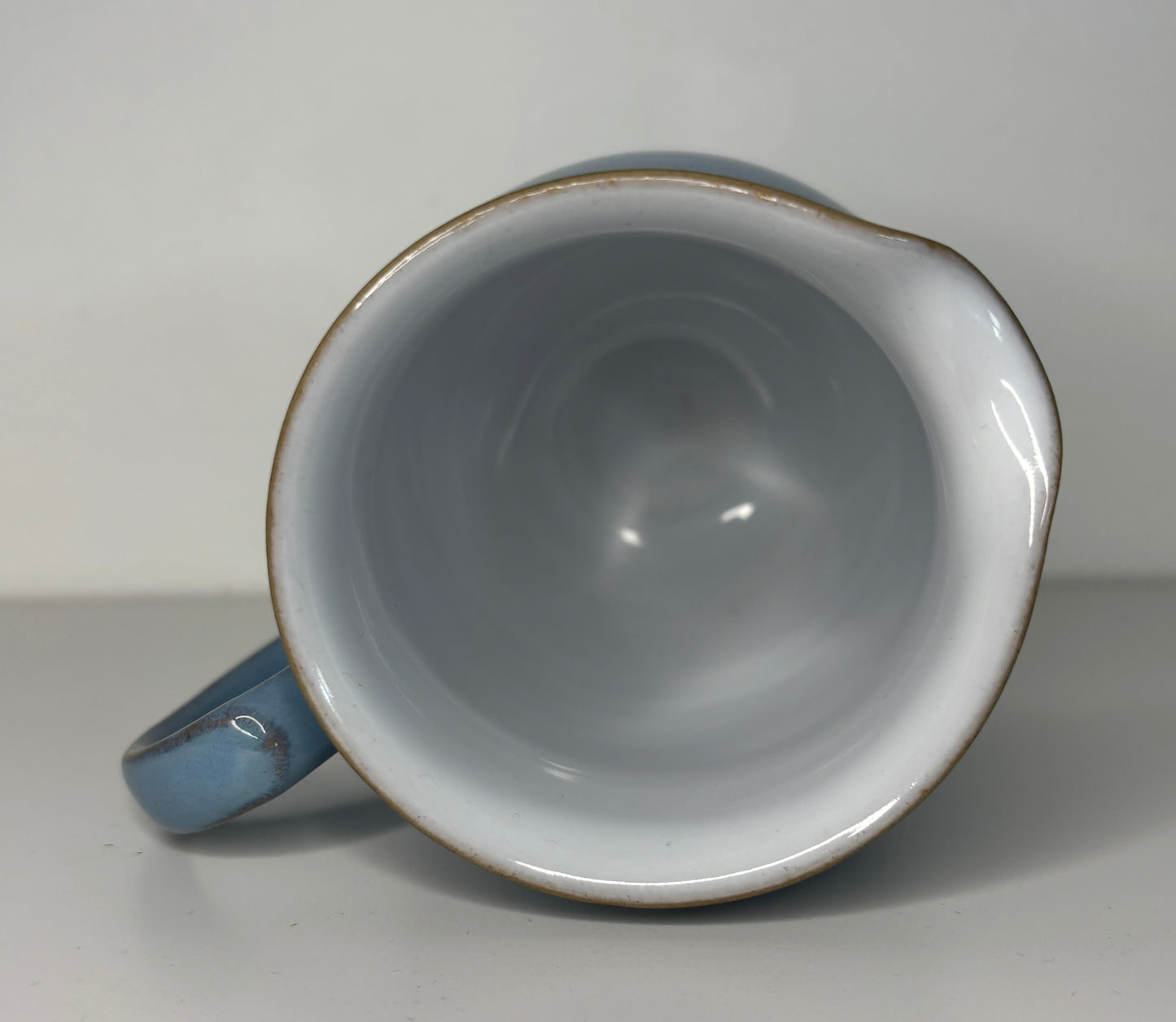 Blue ceramic mug on a gray surface with a white background