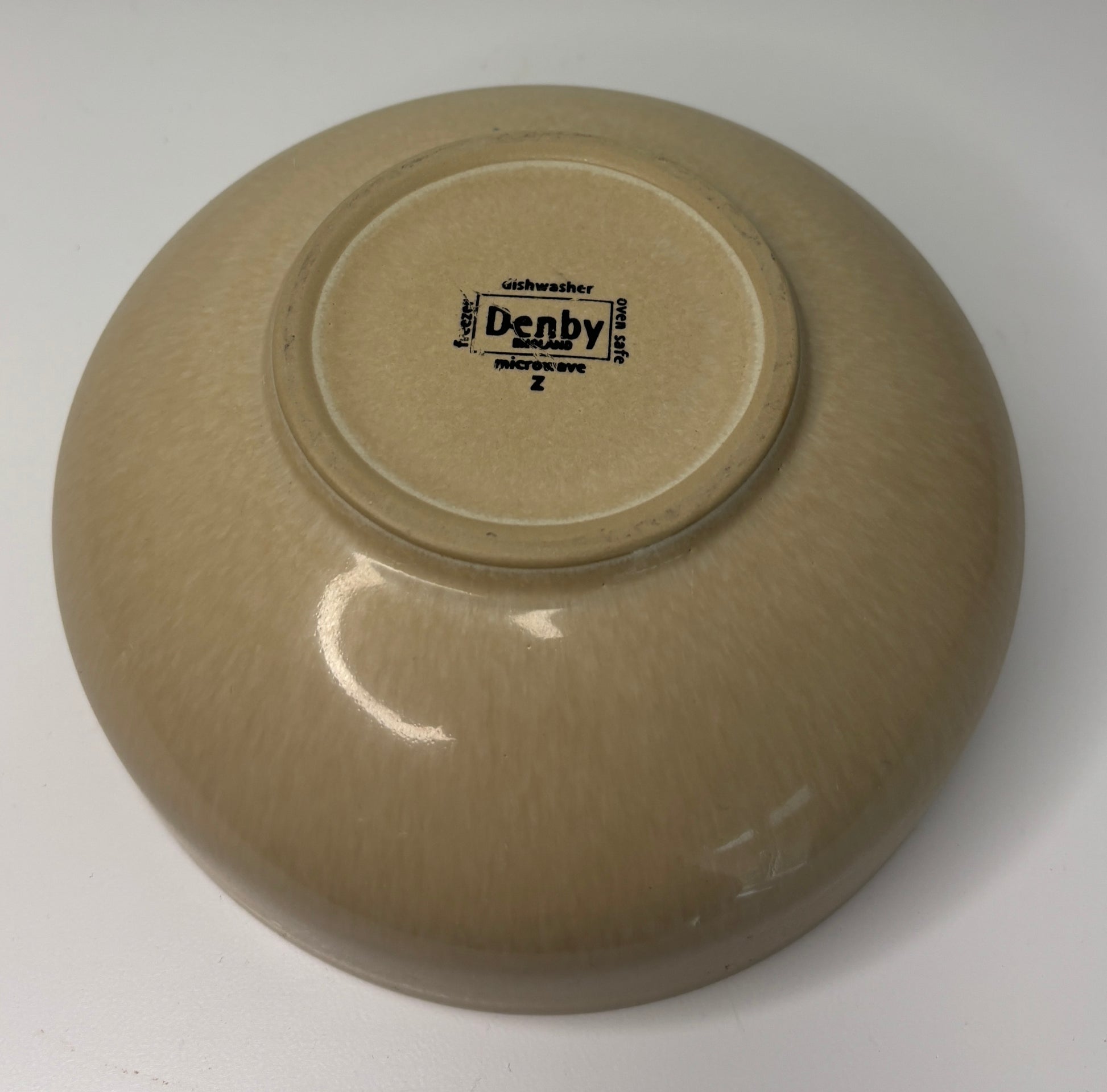 Beige ceramic bowl with 'Denby' branding on a white background