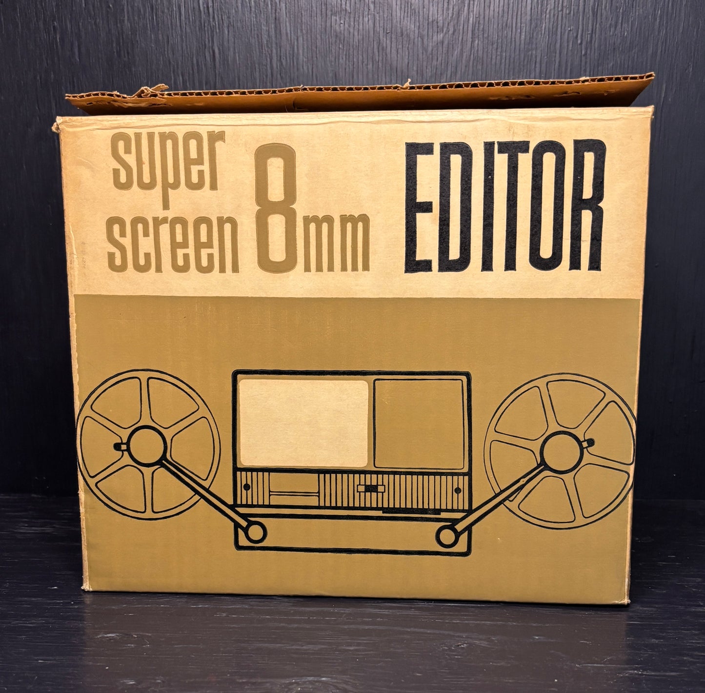 Cardboard box with 'super screen 8mm EDITOR' text and reel-to-reel tape illustration on a black background