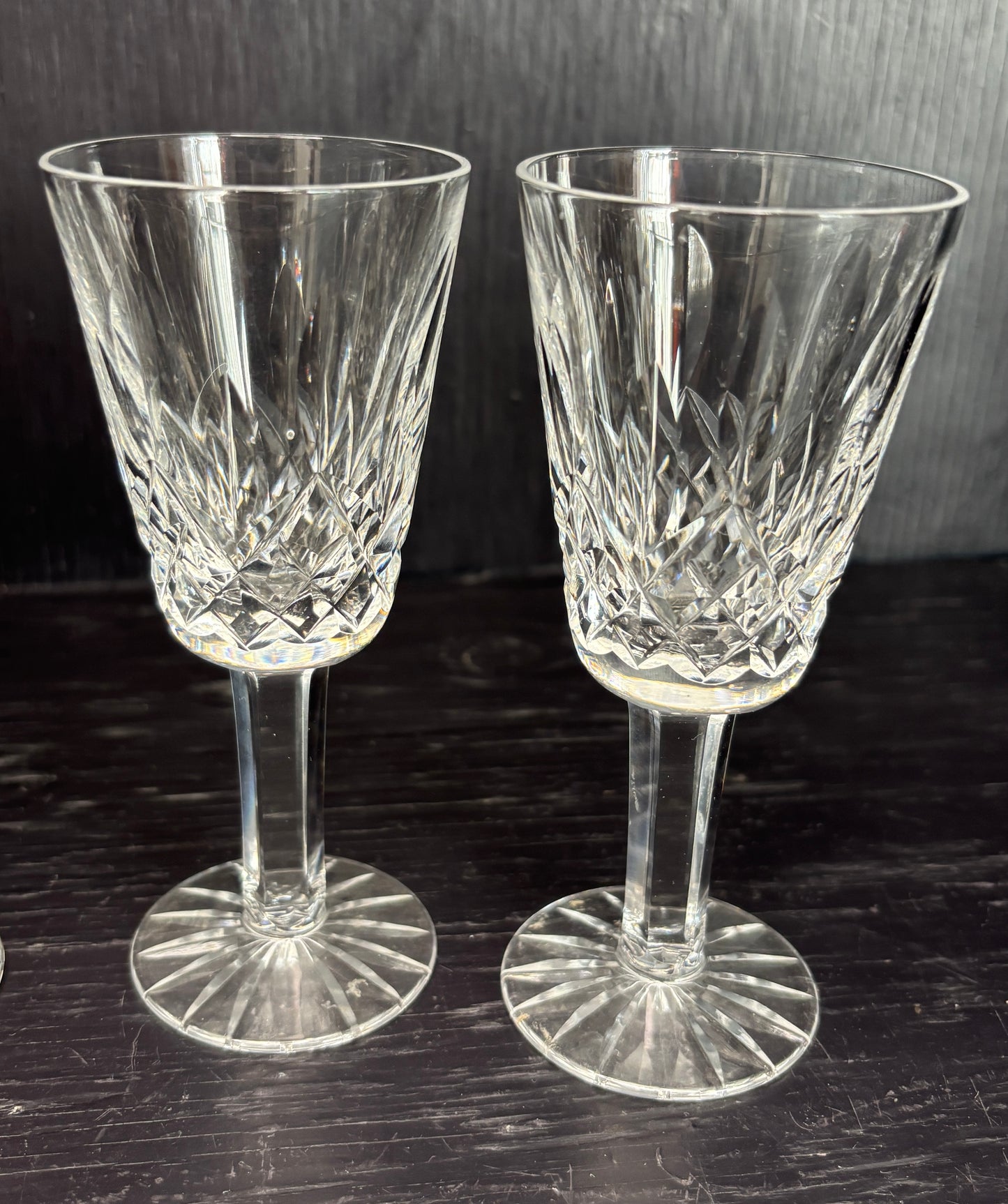 Two crystal sherry glasses on a dark surface