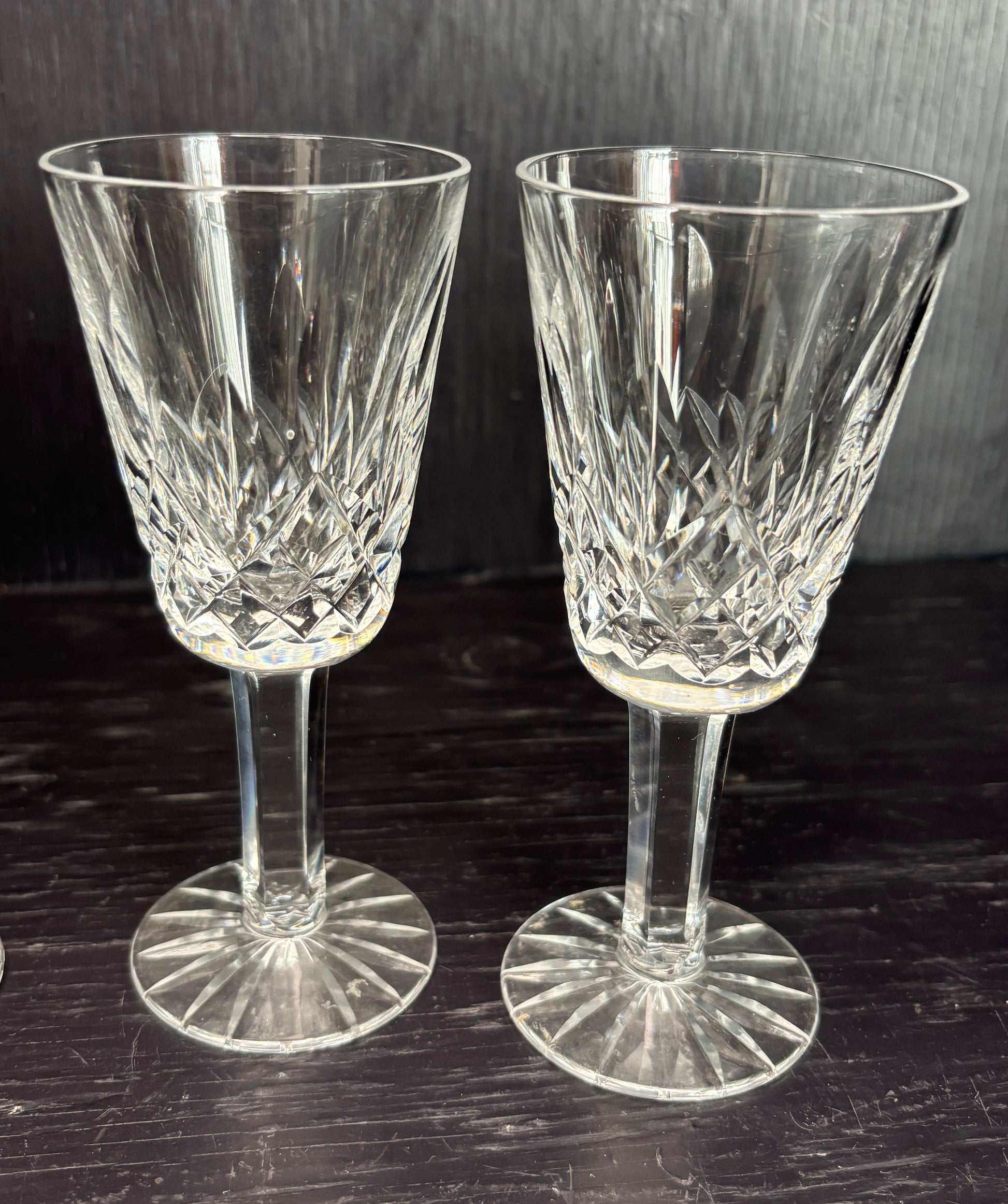 Two crystal sherry glasses on a dark surface