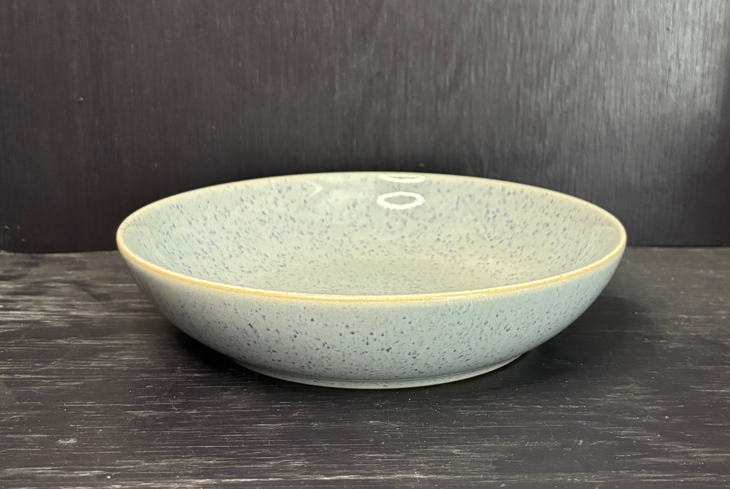 Ceramic bowl with speckled texture on a dark wooden surface