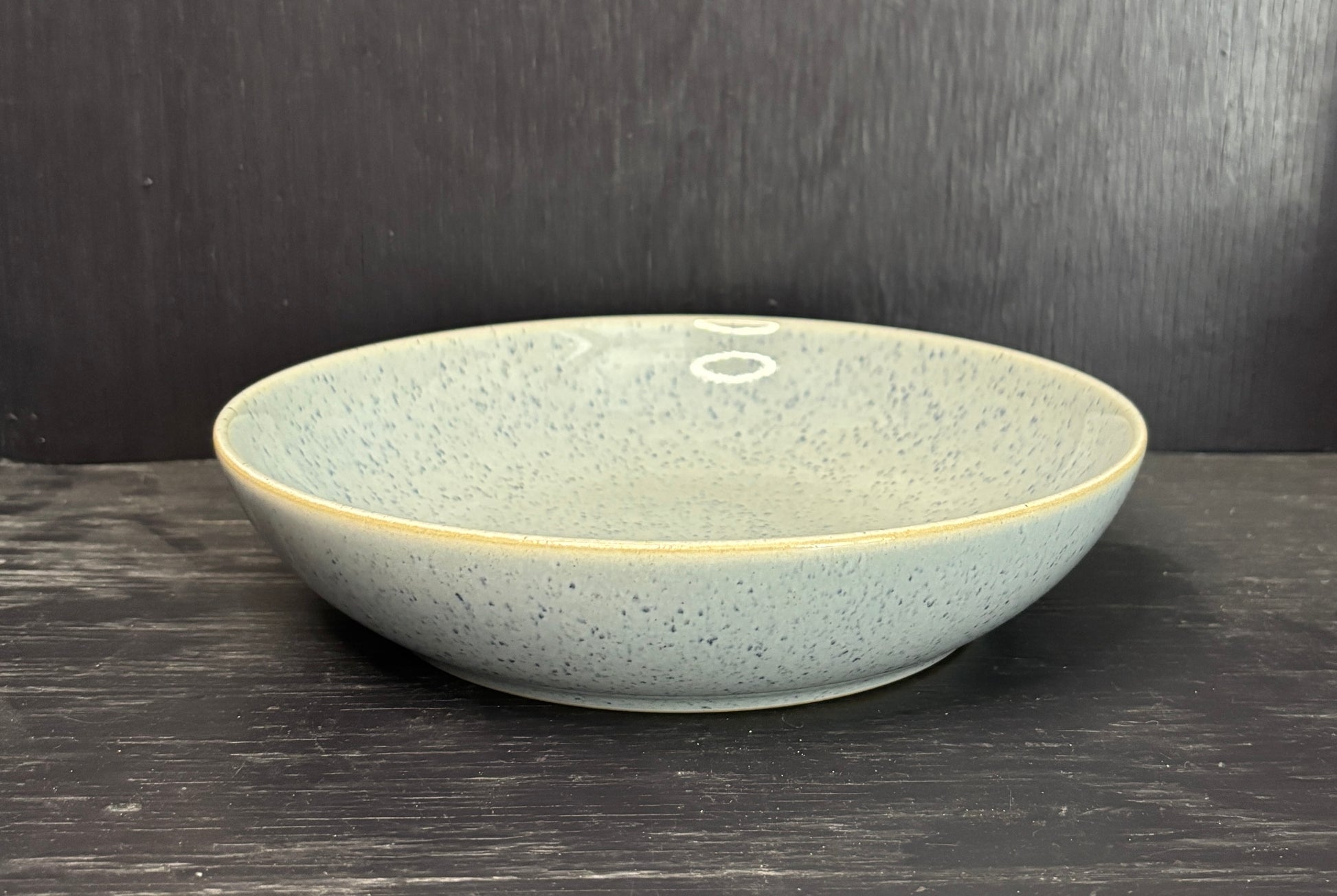 Ceramic bowl with speckled texture on a dark wooden surface