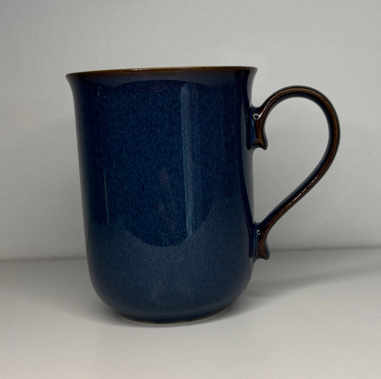 Blue ceramic mug with a handle on a light gray background