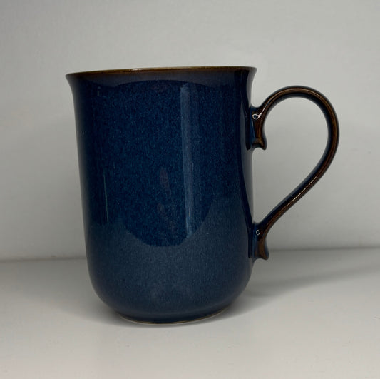 Blue ceramic mug with a handle on a light gray background