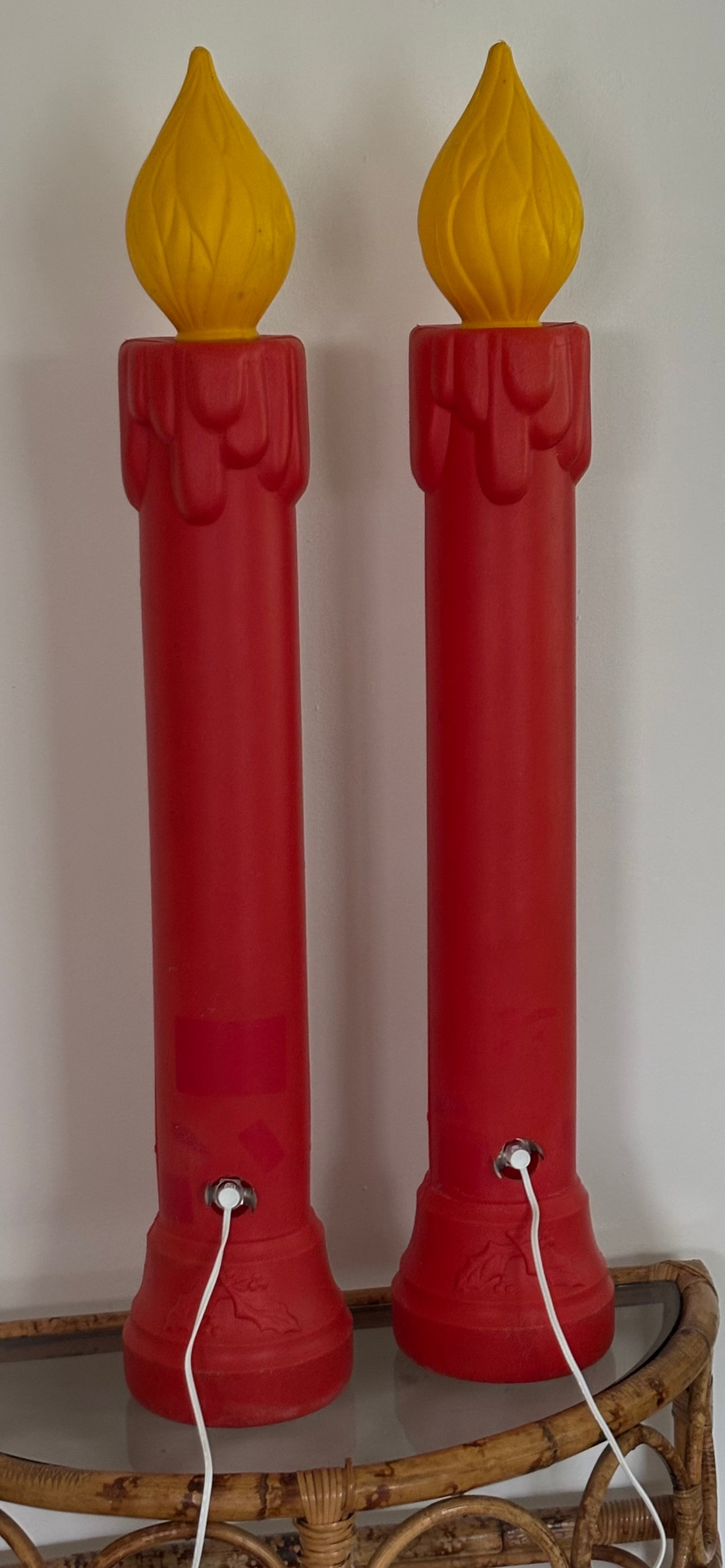 Two red candle-shaped lamps with yellow flame tops on a white background.