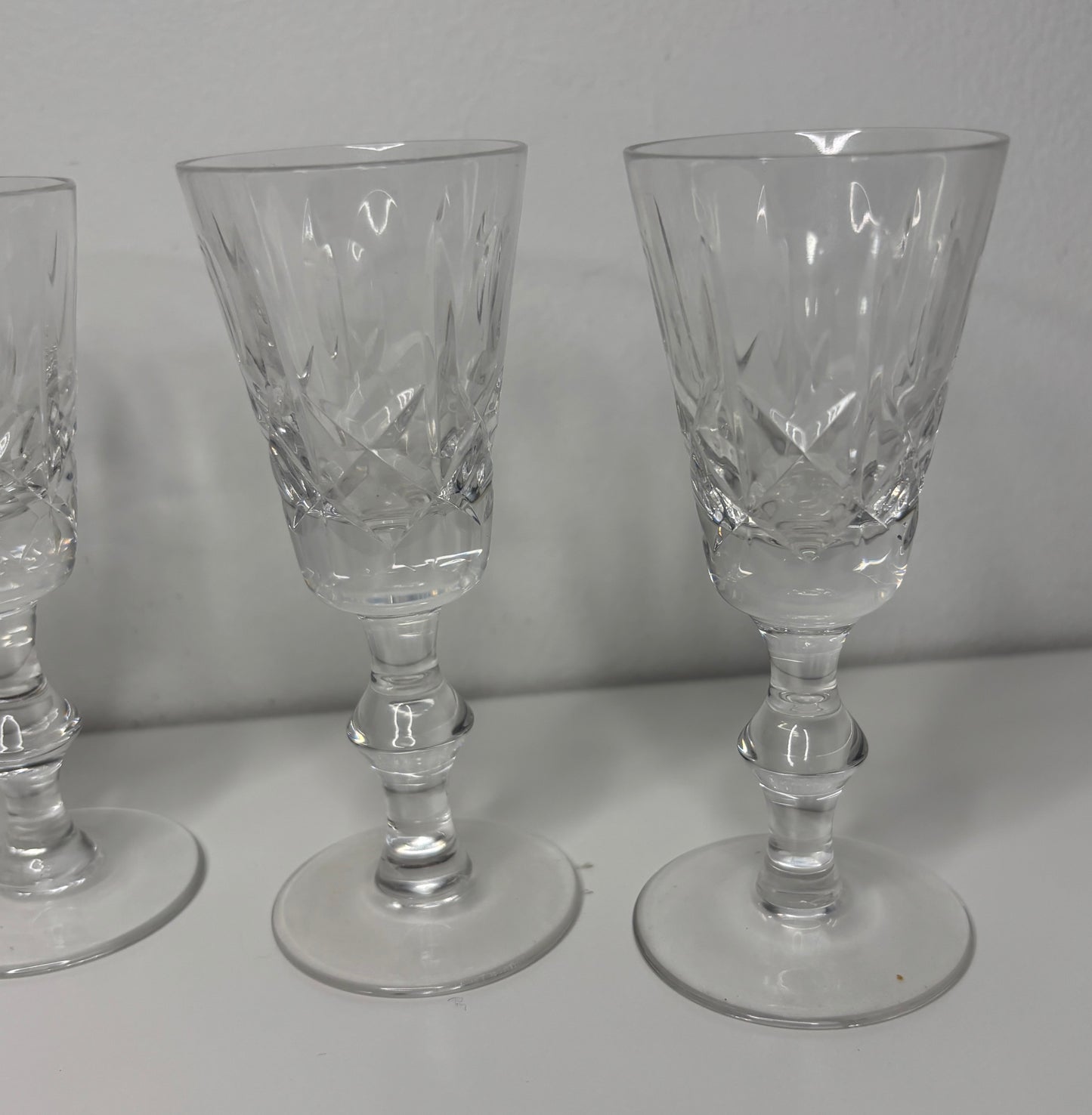Set of three crystal glasses with intricate designs on a white surface and gray background