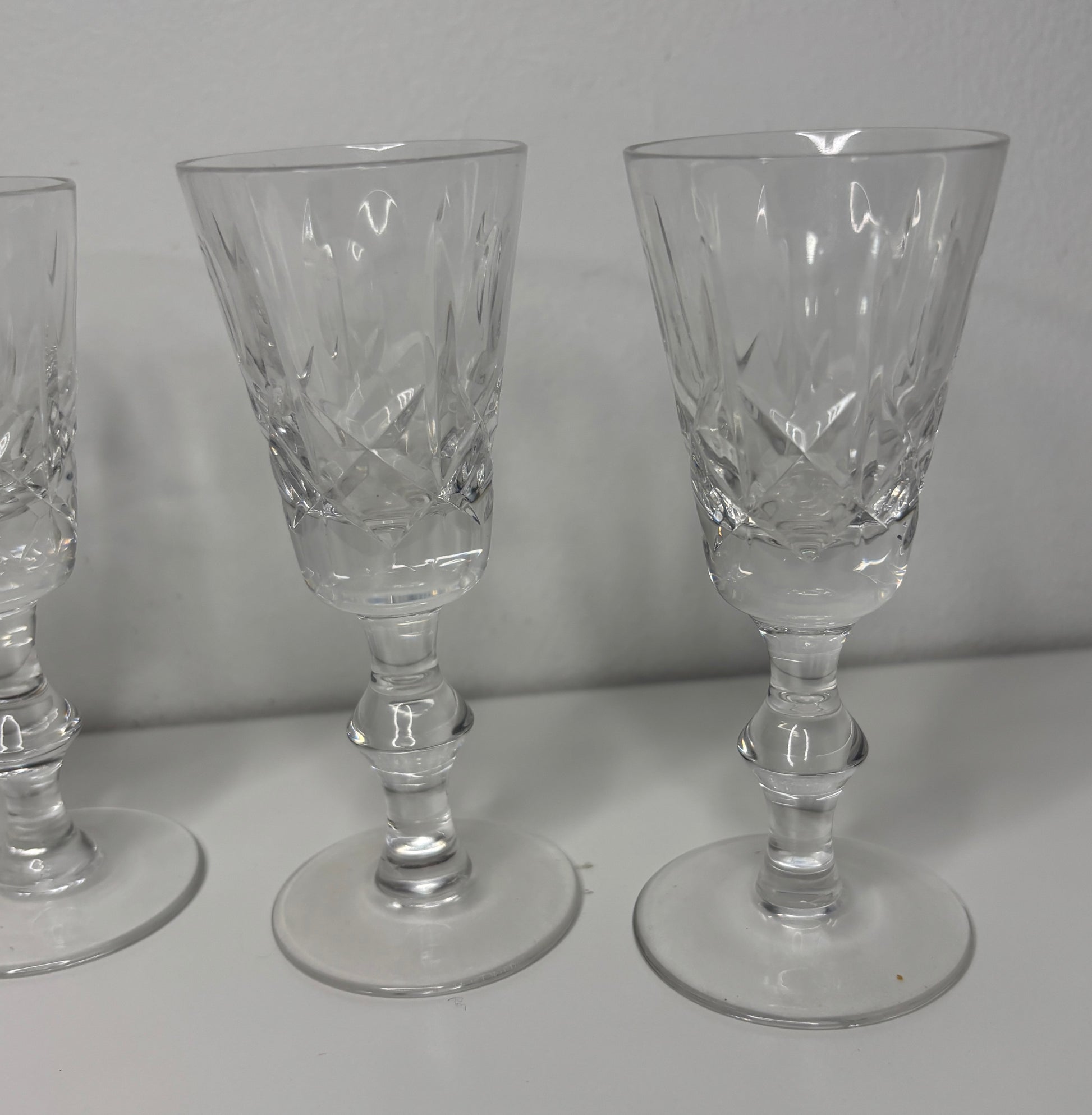 Set of three crystal glasses with intricate designs on a white surface and gray background