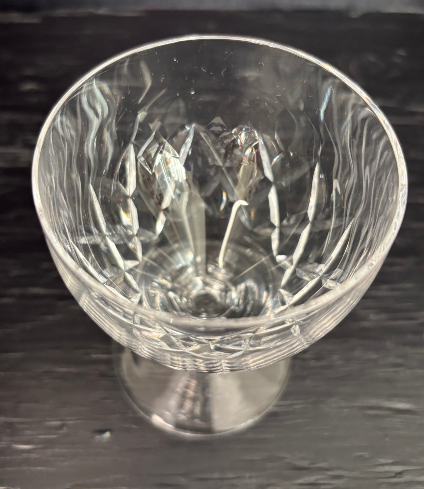Clear glass goblet with intricate cut patterns on a dark background