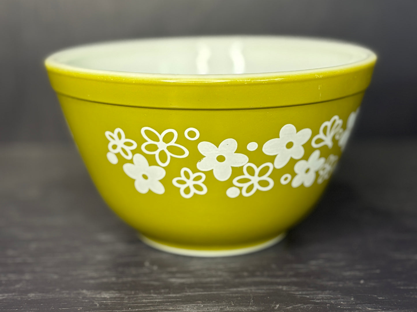 Green bowl with white floral patterns on a dark background