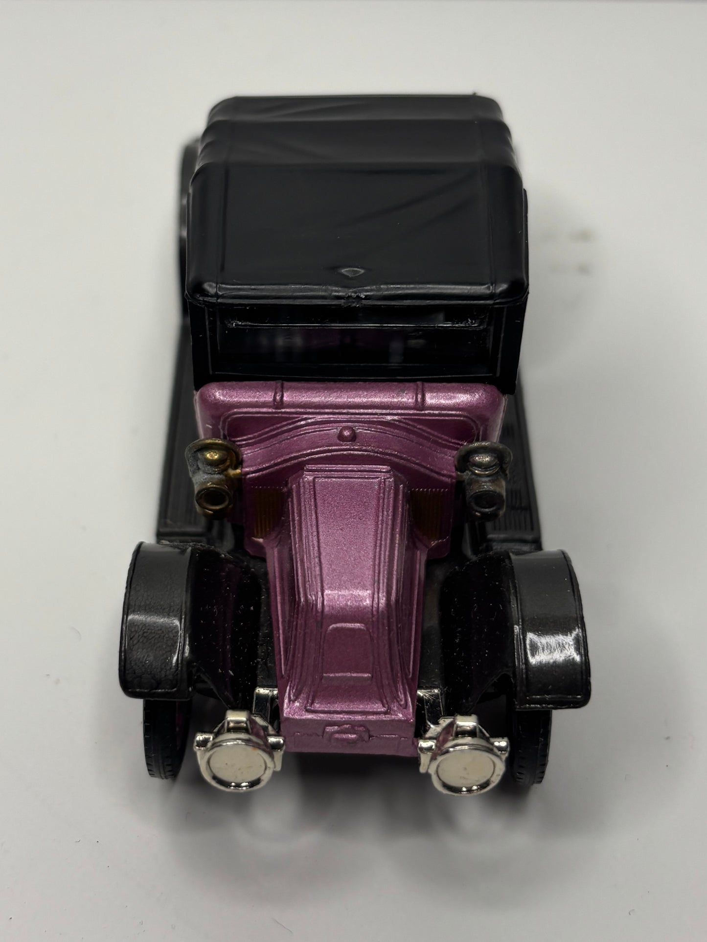 Model of a vintage car with a purple undercarriage on a white background
