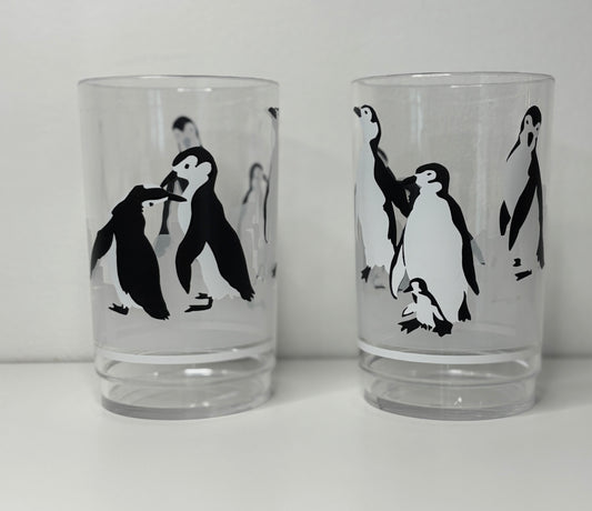 Two glass tumblers with black and white penguin illustrations on a white background