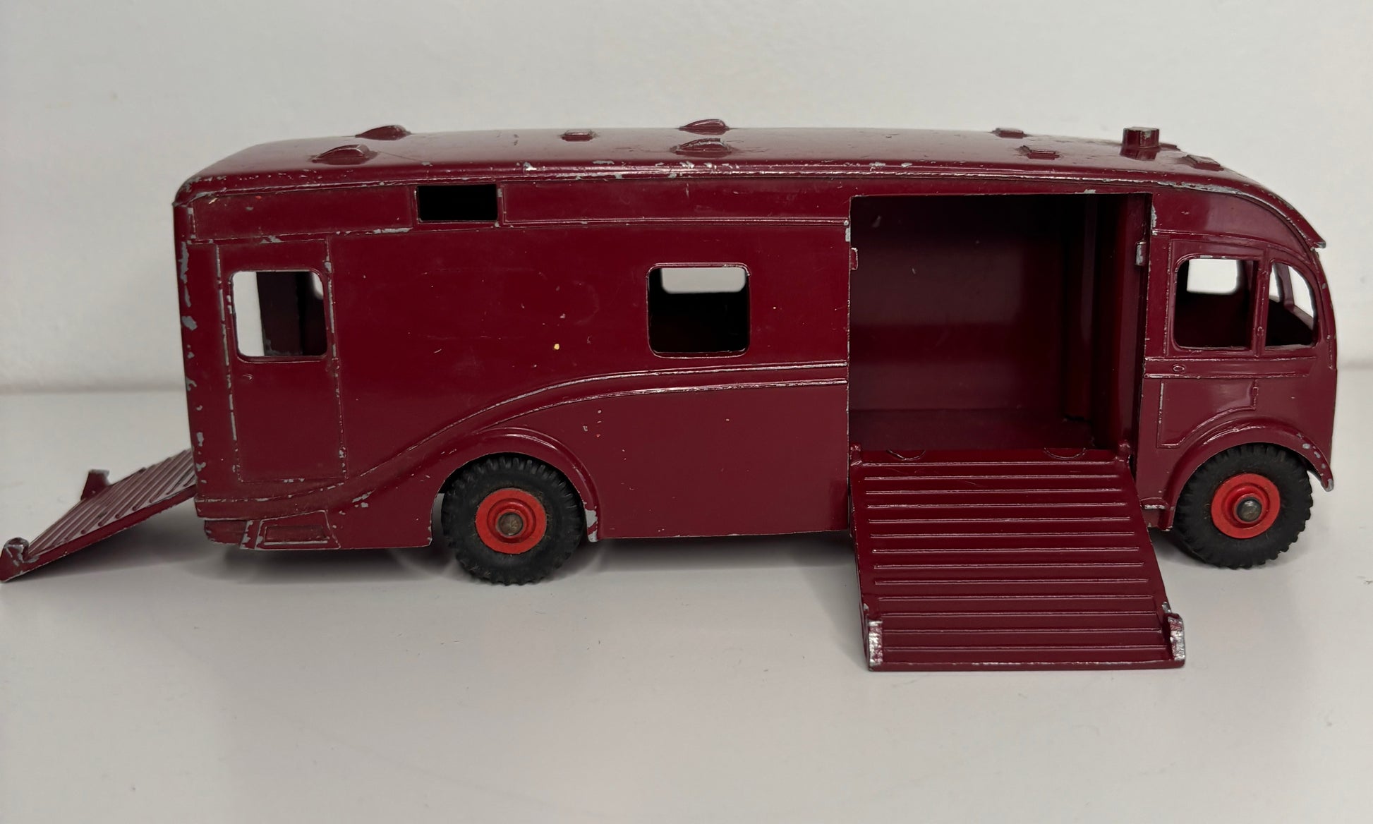 Maroon toy bus with open doors on a white background