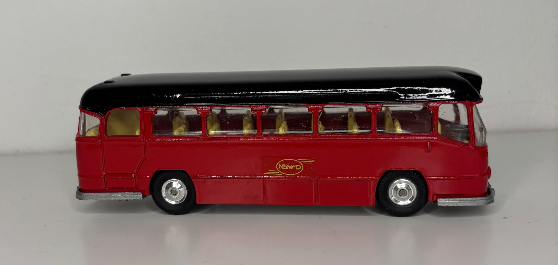Model bus with a black top and red body on a gray background