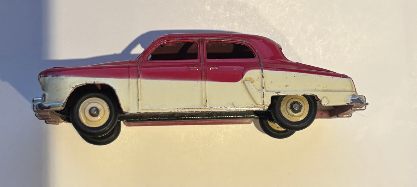 Model of a classic car with a maroon top and white body on a plain background