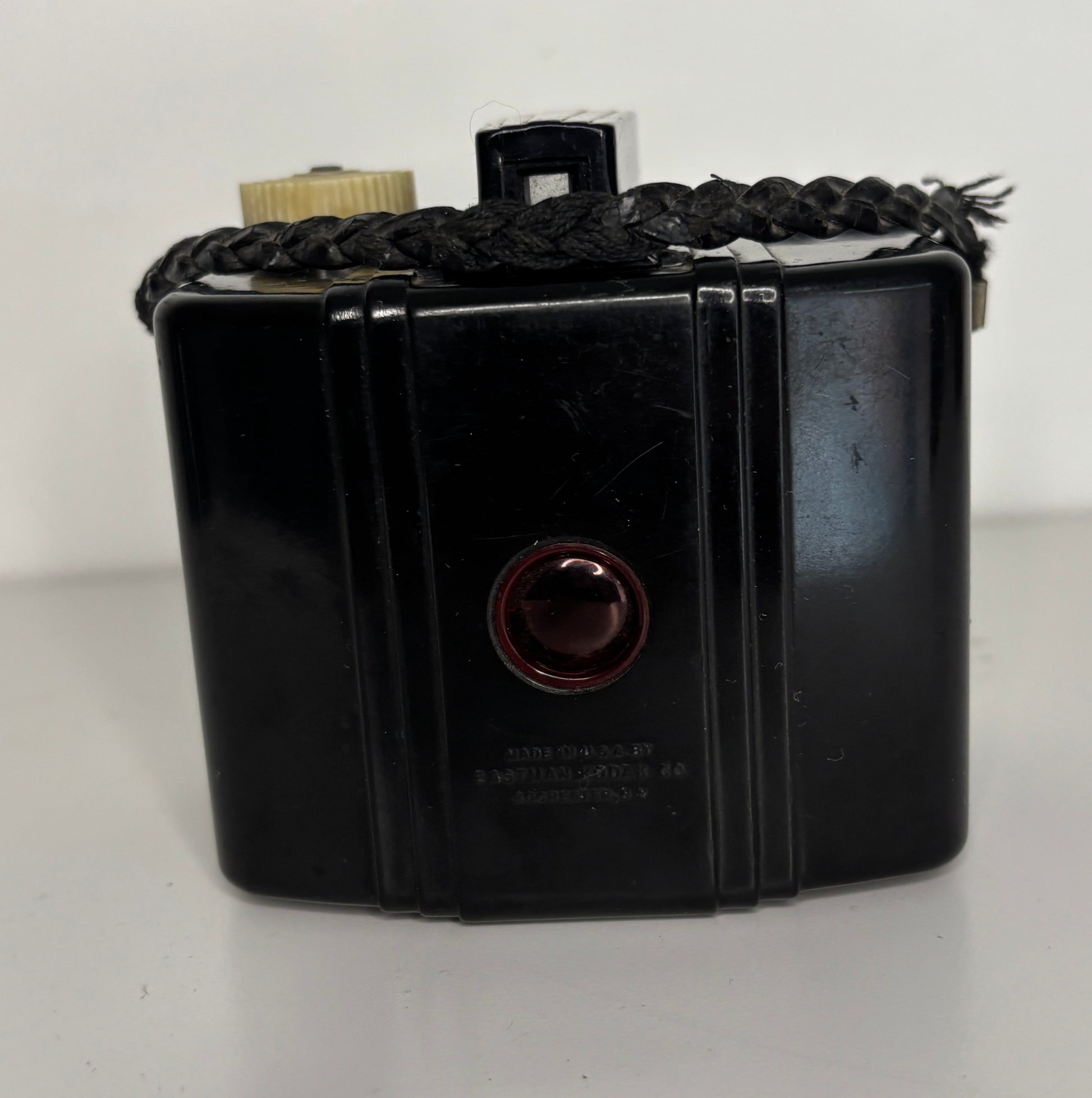 Vintage black rectangular camera with braided handle on a white background