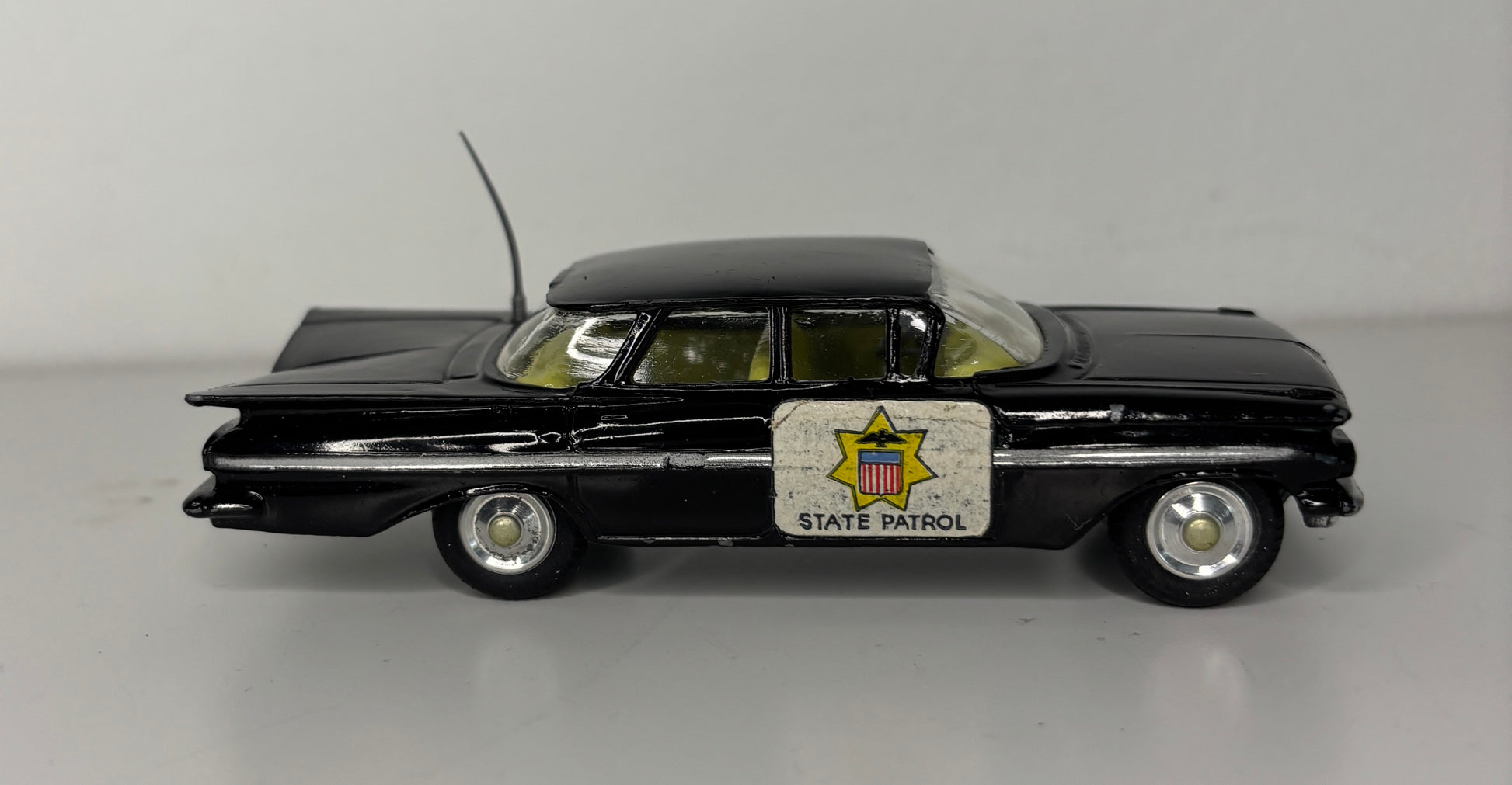 Model of a black police car with 'State Patrol' sign on a gray background