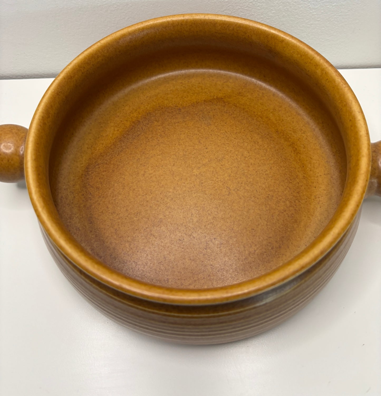 Brown ceramic bowl with handles on a white background