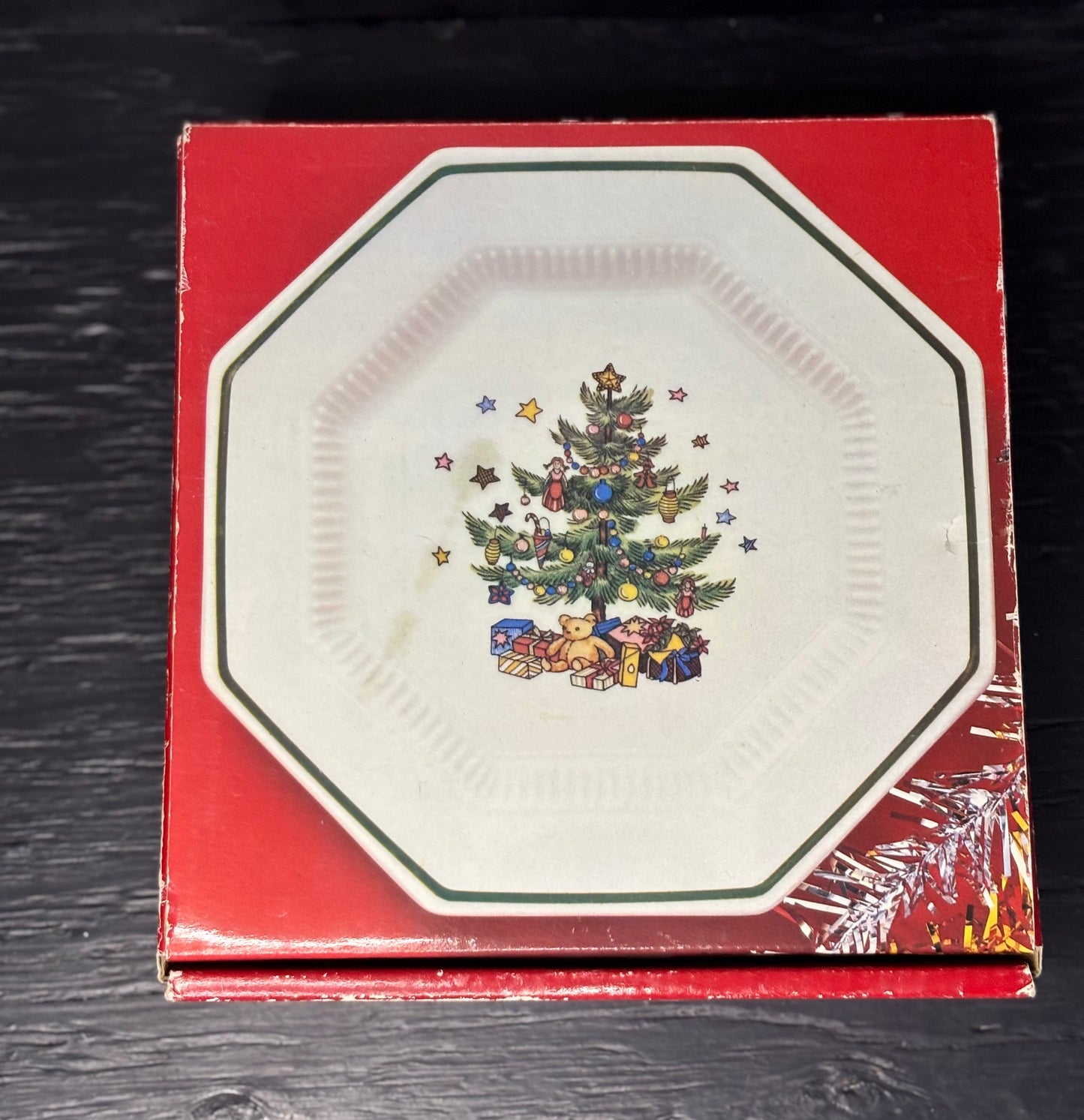 Decorative plate with Christmas tree and presents design on a red box.