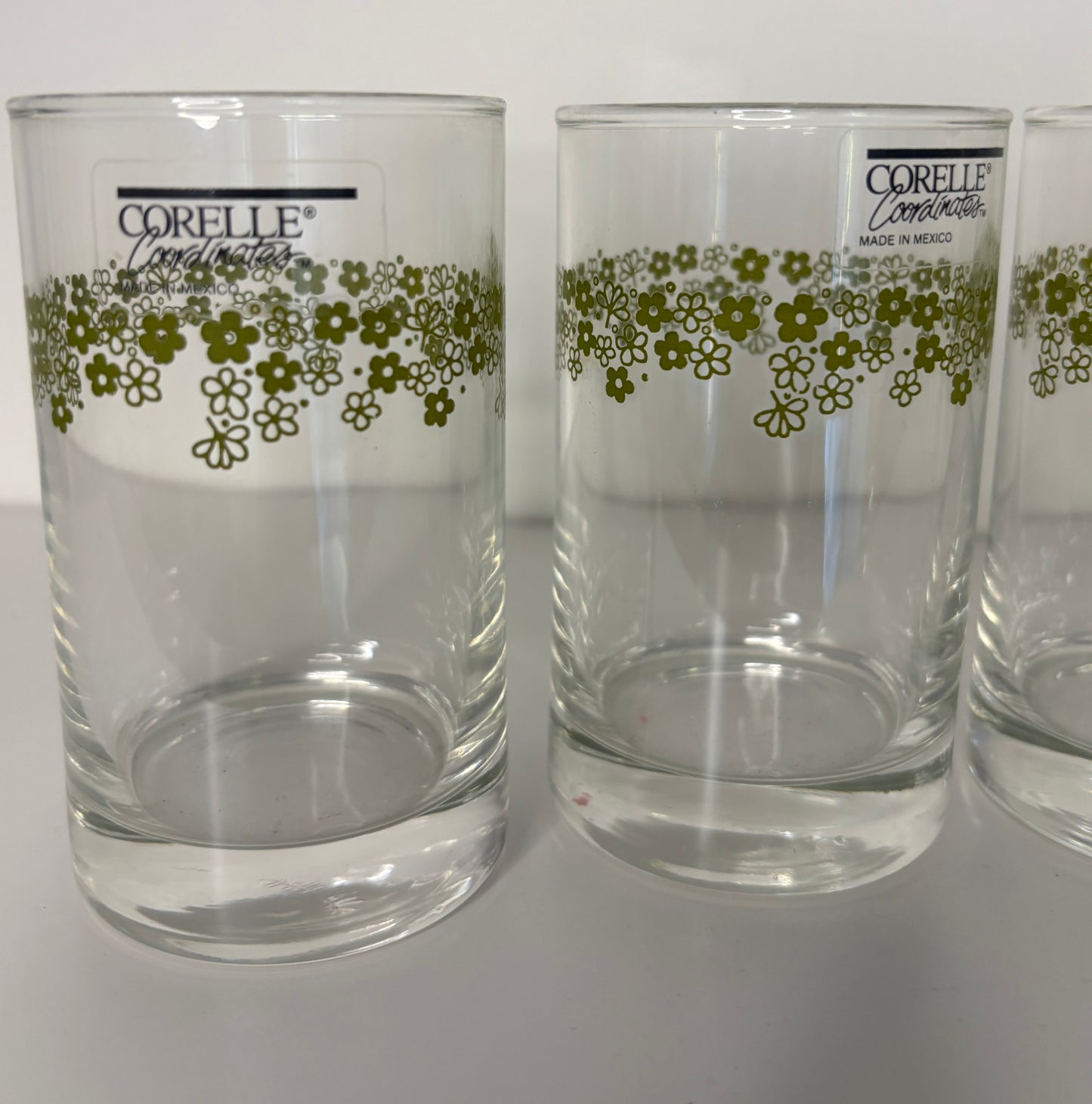Two clear glasses with floral pattern and Corelle branding on a white background