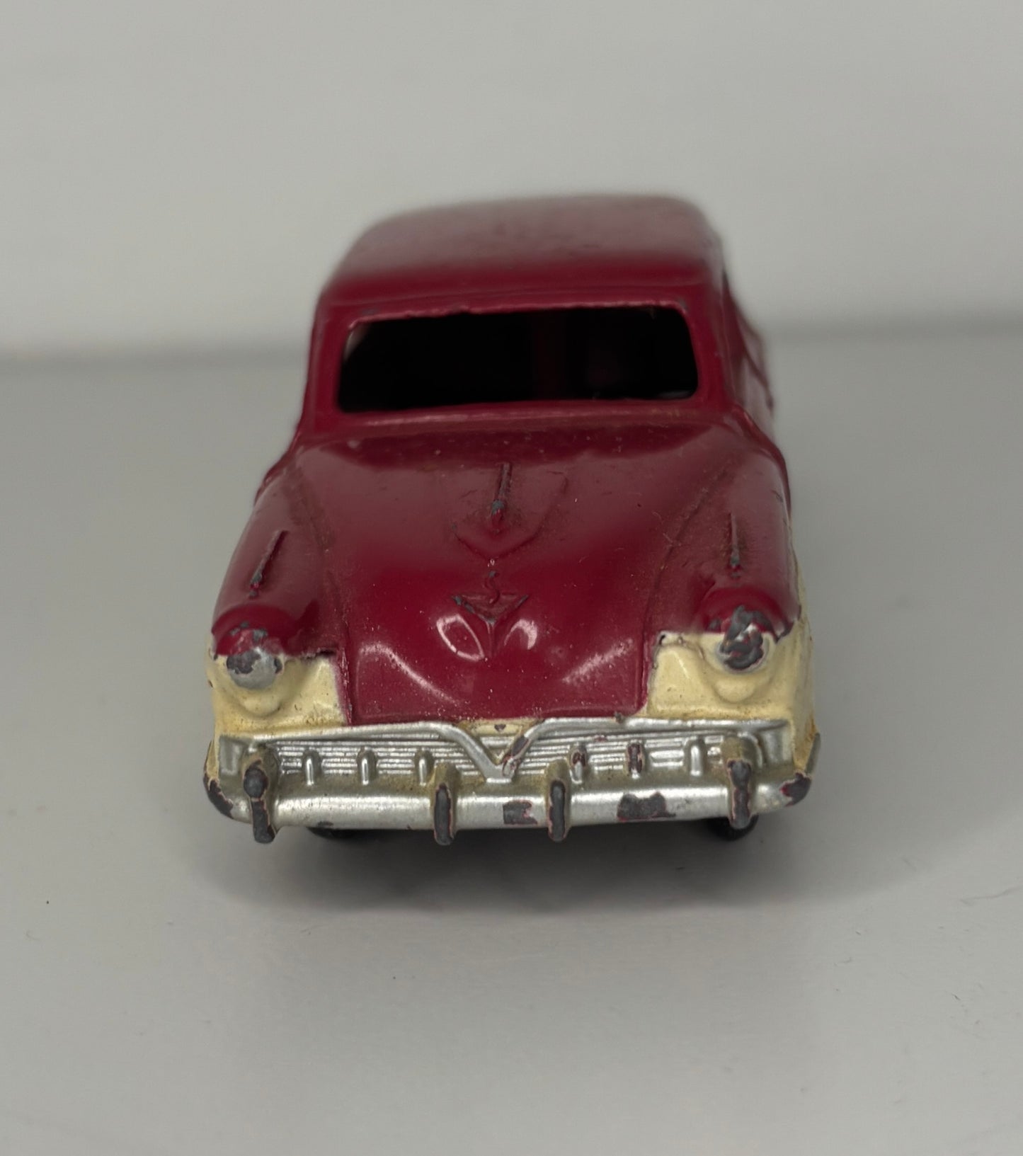 Model car with maroon body and beige bumper on a gray background