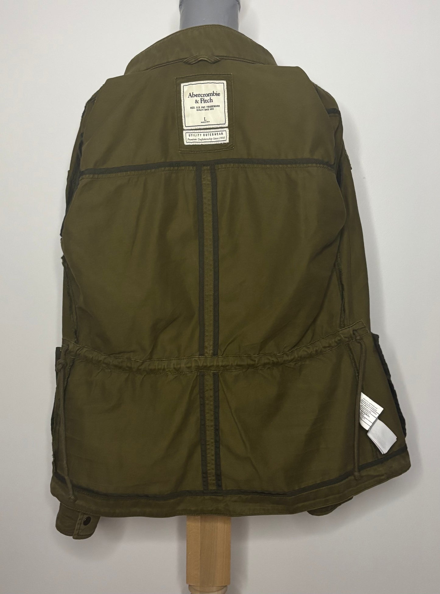 Green jacket on a mannequin with a visible brand label against a white background