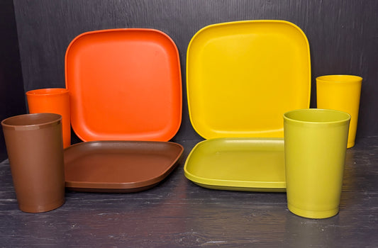 Set of colorful plastic plates and cups on a dark surface