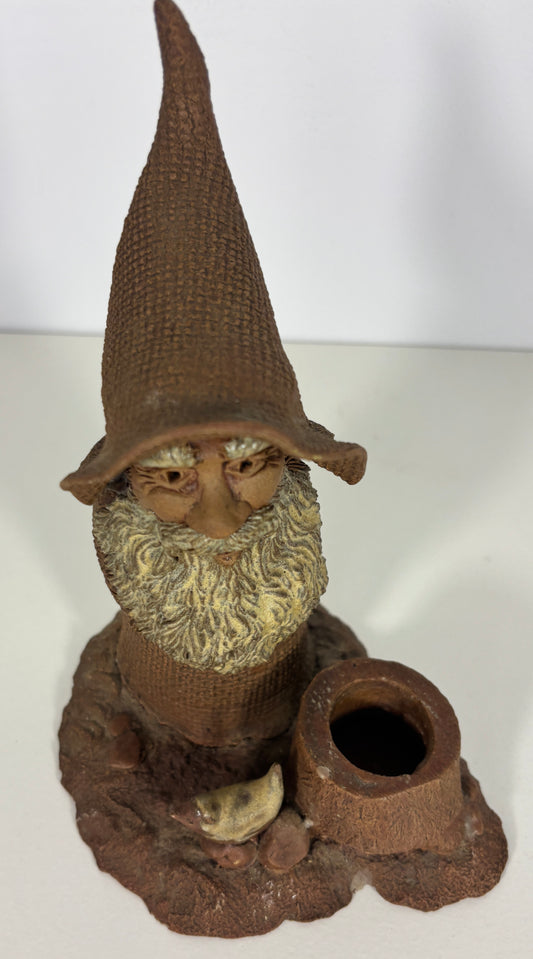 Gnome figurine with a pointed hat and beard, sitting on a white surface.